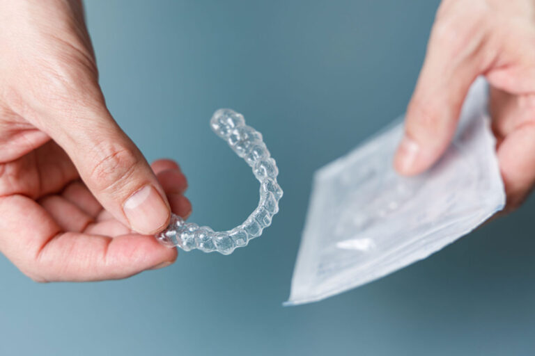 Hands holding a clear aligner and its sealed packaging