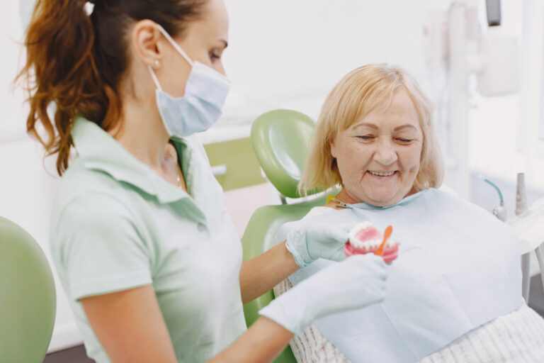 Dentist showing a denture to a smiling senior patient